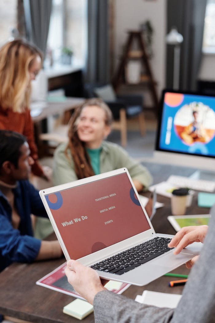 Team discussing project in modern office with laptop displaying presentation.